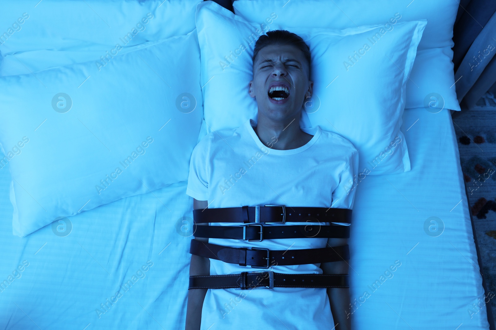 Photo of Man in sleepwalking condition screaming on bed, top view