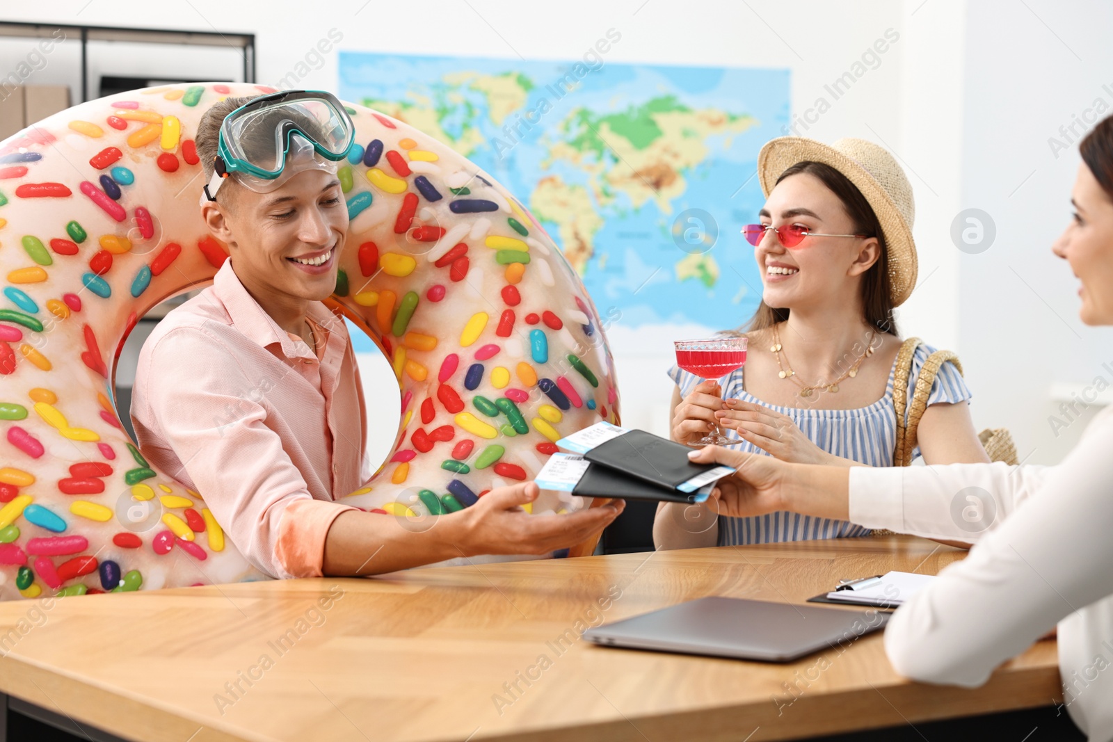 Photo of Happy couple planning vacation with travel agent at wooden table in office