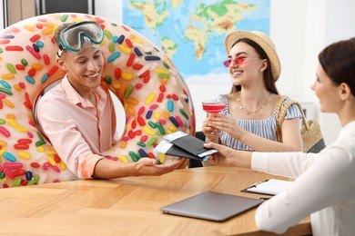 Photo of Happy couple planning vacation with travel agent at wooden table in office