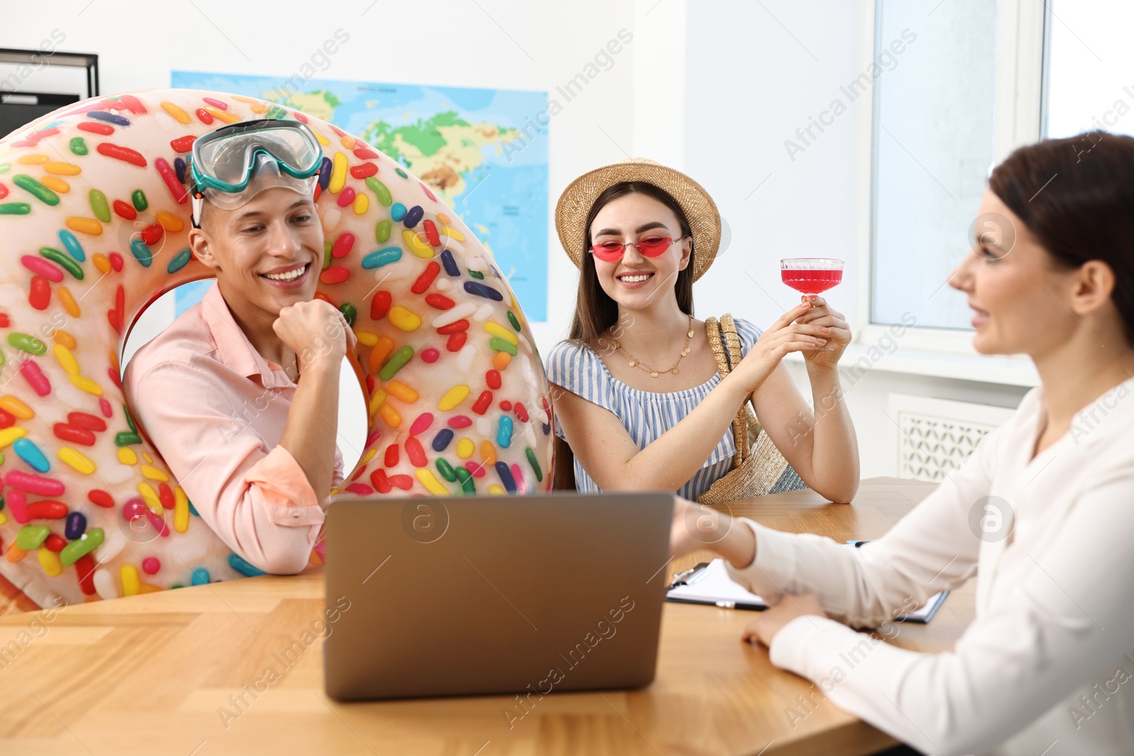 Photo of Happy couple planning vacation with travel agent at wooden table in office