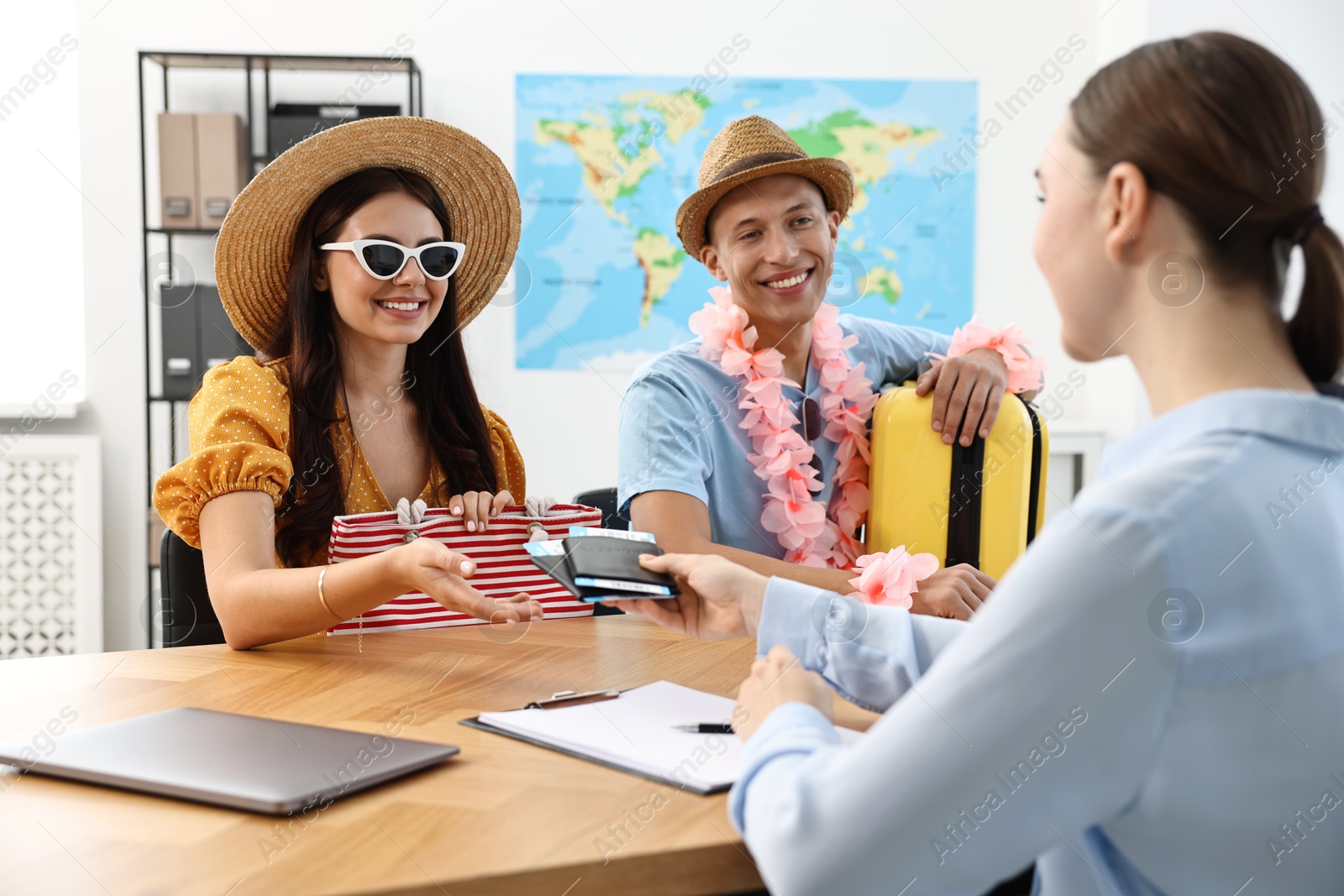 Photo of Happy couple planning vacation with travel agent at wooden table in office