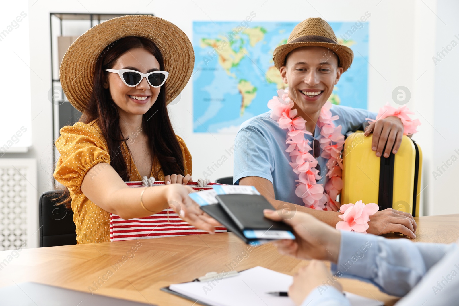 Photo of Happy couple planning vacation with travel agent at wooden table in office