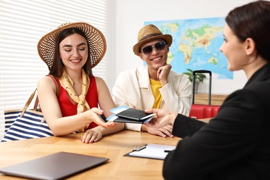 Photo of Happy couple planning vacation with travel agent at wooden table in office