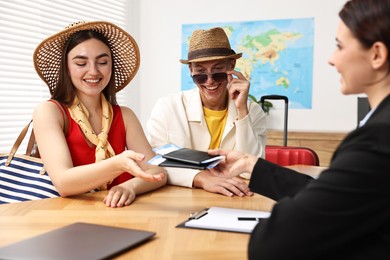 Photo of Happy couple planning vacation with travel agent at wooden table in office