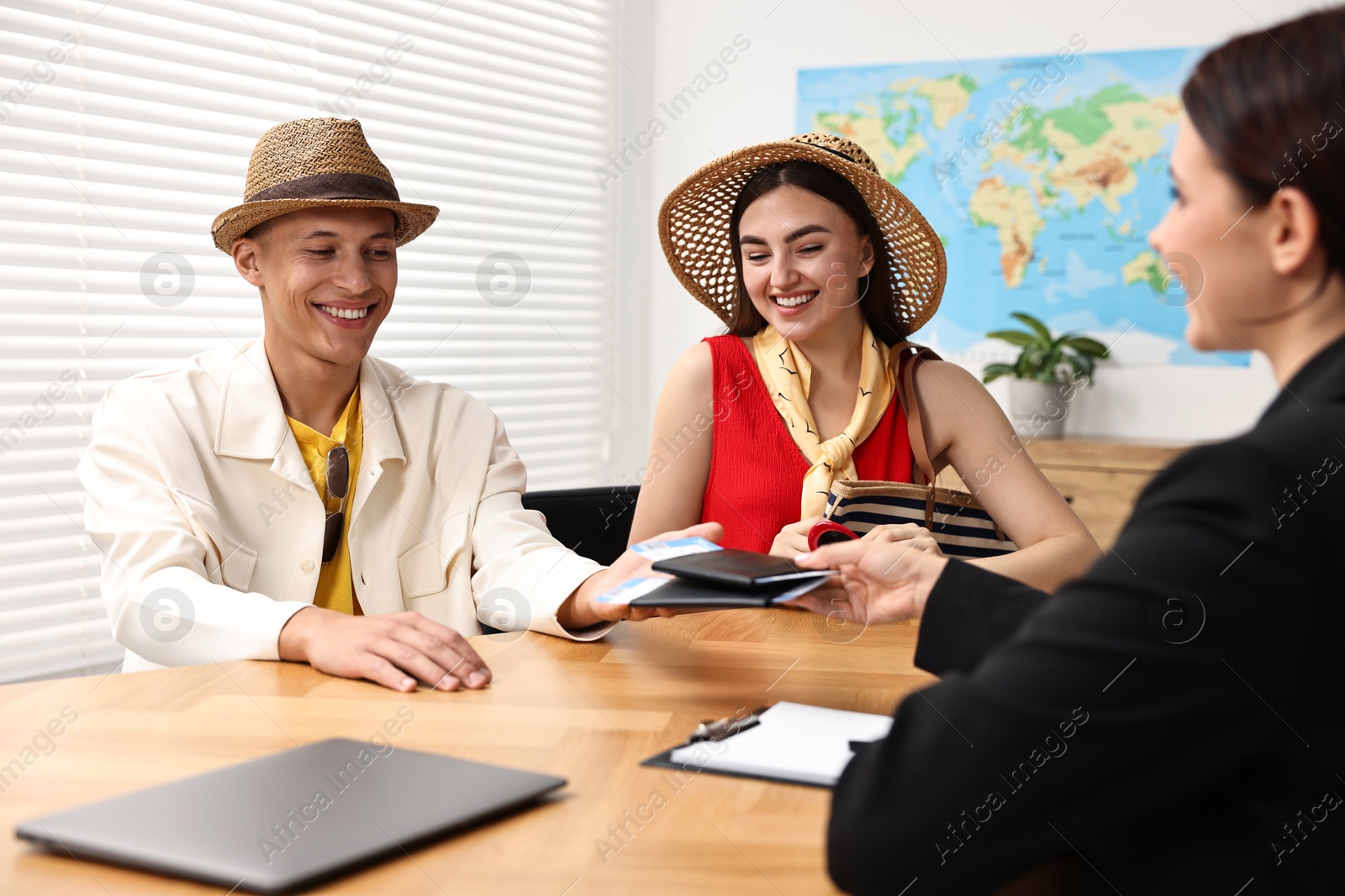 Photo of Happy couple planning vacation with travel agent at wooden table in office