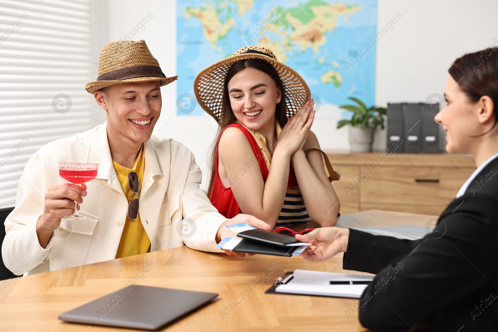 Photo of Happy couple planning vacation with travel agent at wooden table in office