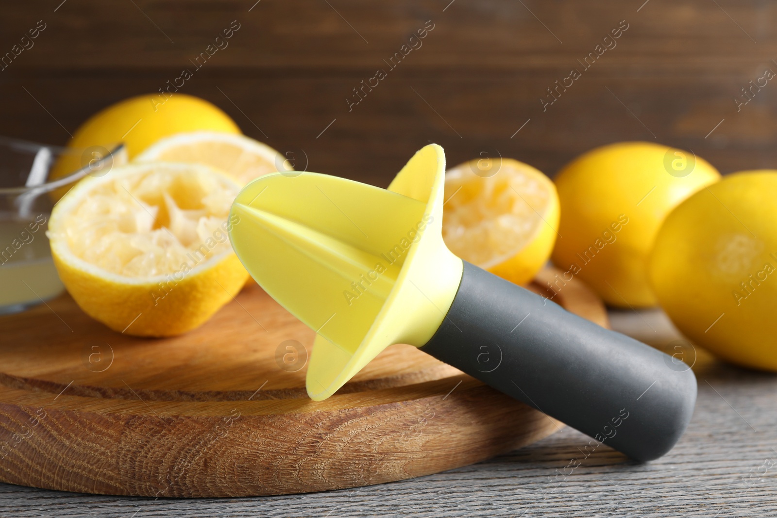 Photo of Plastic juicer and fresh lemons on grey wooden table, closeup