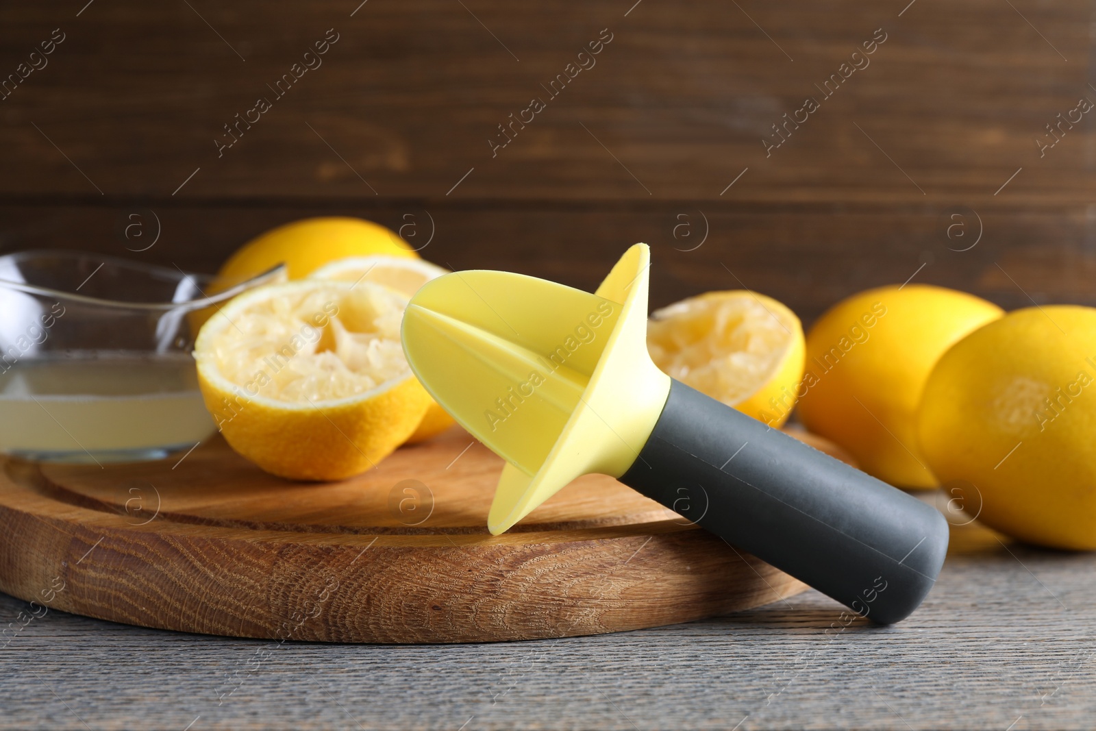 Photo of Plastic juicer and fresh lemons on grey wooden table, closeup