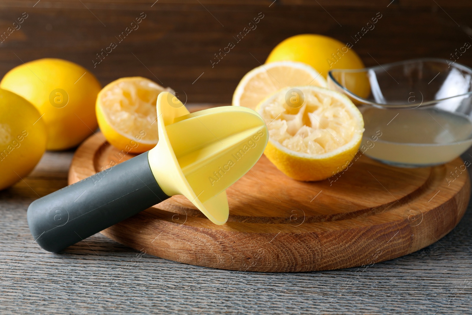 Photo of Plastic juicer and fresh lemons on grey wooden table, closeup