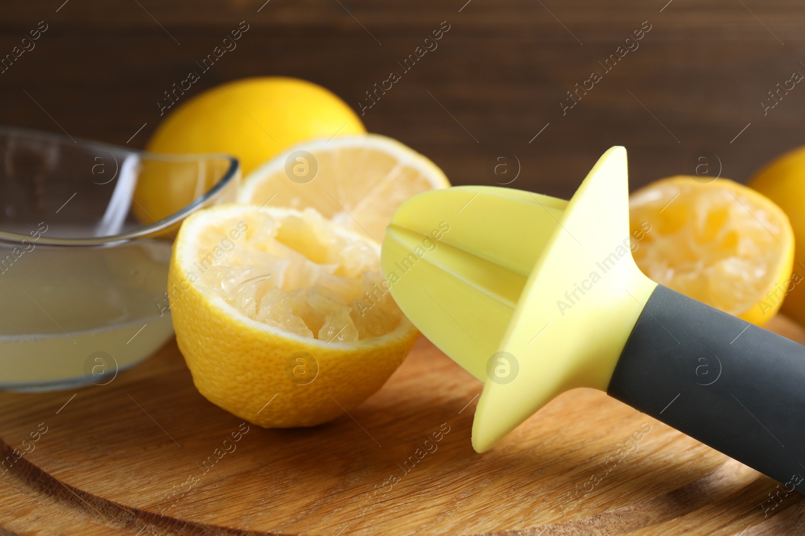 Photo of Plastic juicer and fresh lemons on grey wooden table, closeup