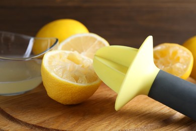 Photo of Plastic juicer and fresh lemons on grey wooden table, closeup