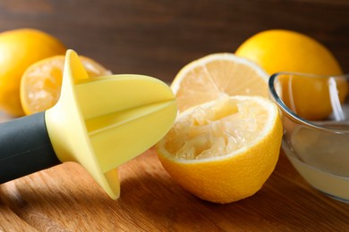 Photo of Plastic juicer and fresh lemons on grey wooden table, closeup