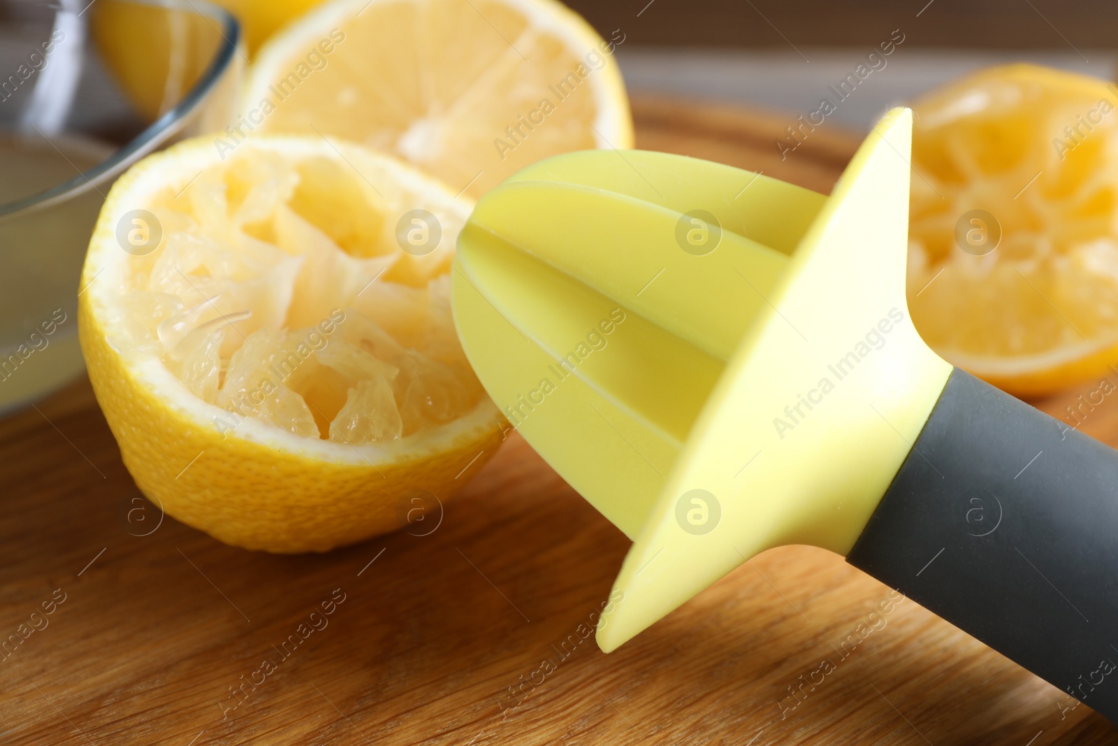 Photo of Plastic juicer and fresh lemons on grey wooden table, closeup