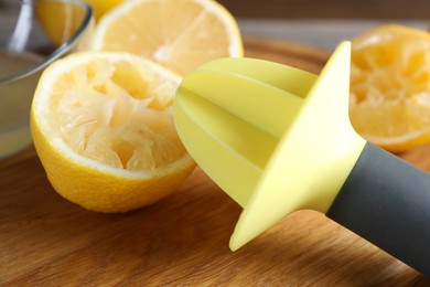 Photo of Plastic juicer and fresh lemons on grey wooden table, closeup