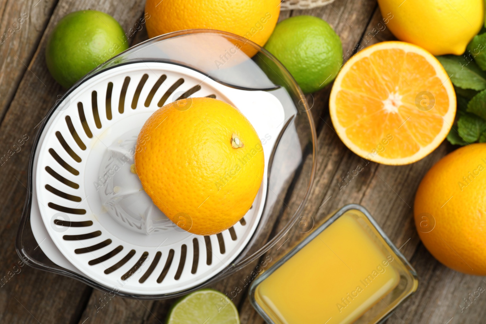 Photo of Plastic juicer, fresh oranges and limes on wooden table, flat lay