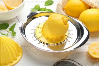 Photo of Plastic juicer and fresh lemons on white wooden table, closeup