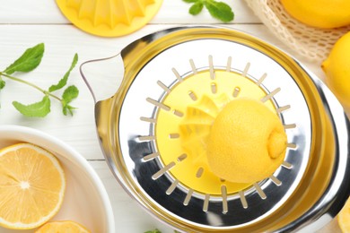 Photo of Plastic juicer and fresh lemons on white wooden table, flat lay