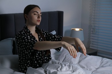 Photo of Young woman suffering from sleepwalking on bed at home