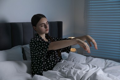 Photo of Young woman suffering from sleepwalking on bed at home