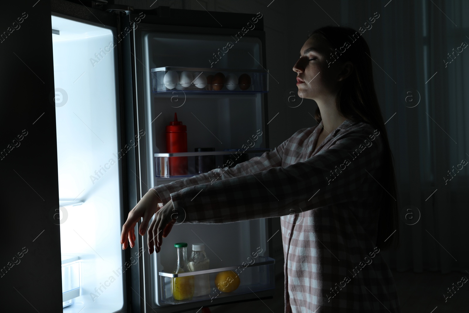 Photo of Young woman suffering from sleepwalking near fridge at home