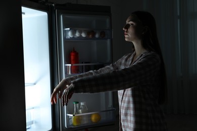 Photo of Young woman suffering from sleepwalking near fridge at home