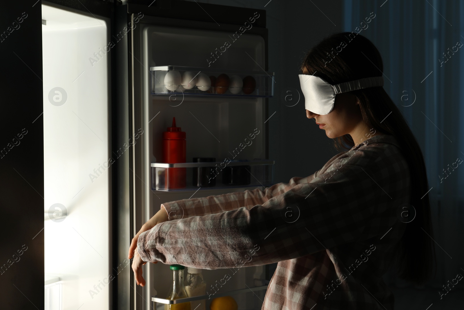 Photo of Young woman suffering from sleepwalking near fridge at home