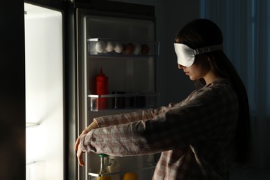 Young woman suffering from sleepwalking near fridge at home