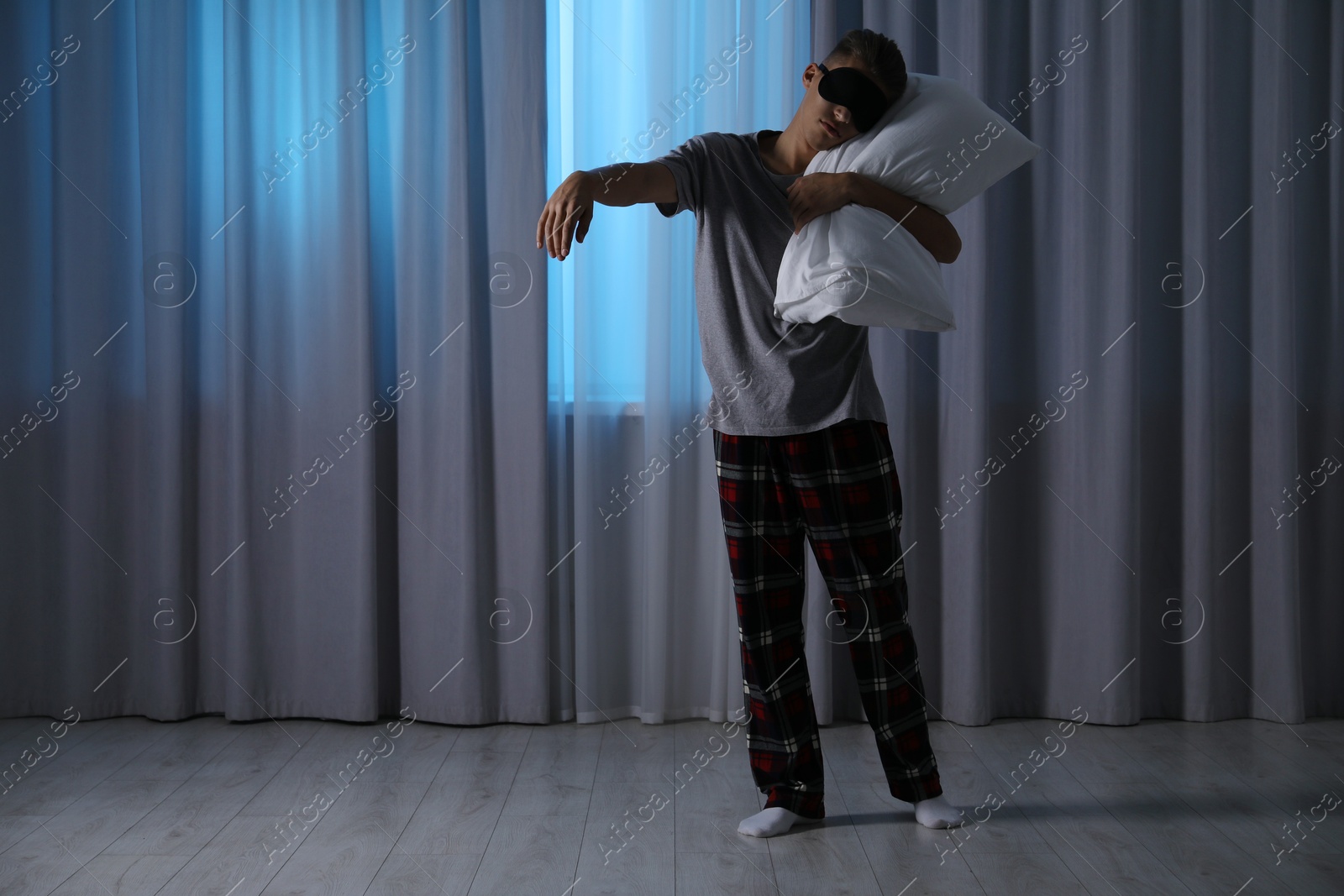 Photo of Young man suffering from sleepwalking at home, space for text