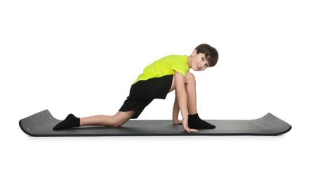 Photo of Boy exercising on fitness mat against white background. Sport activity