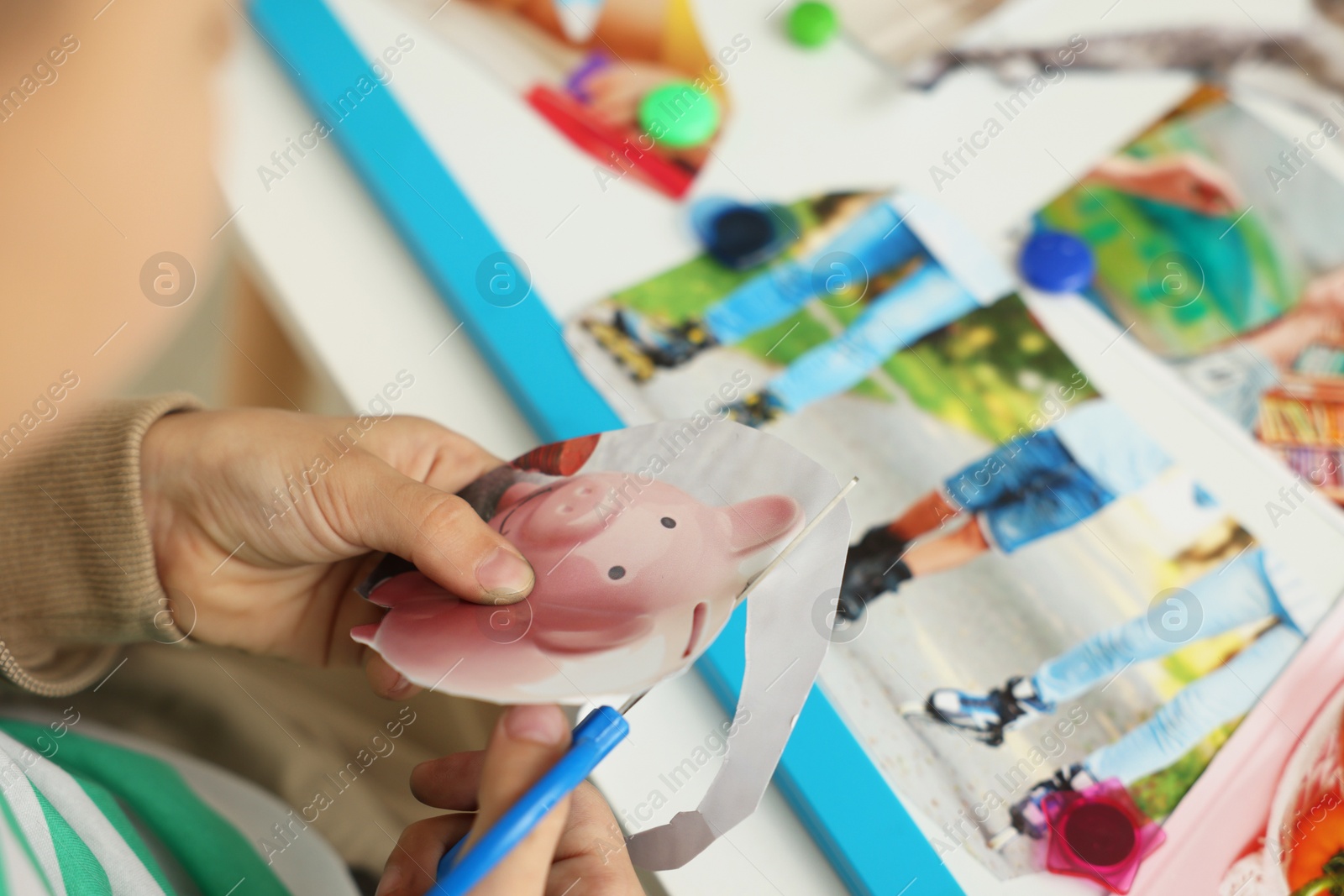 Photo of Creating vision board. Little boy cutting out picture at table indoors, closeup