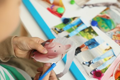 Photo of Creating vision board. Little boy cutting out picture at table indoors, closeup