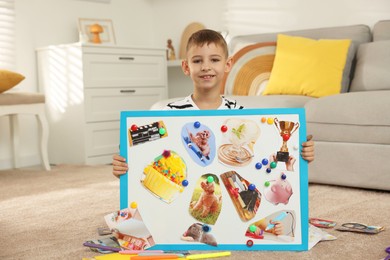 Photo of Little boy holding vision board with different pictures on floor at home