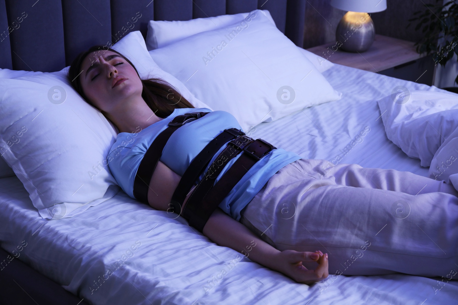 Photo of Sleepwalker fastened with belts lying on bed