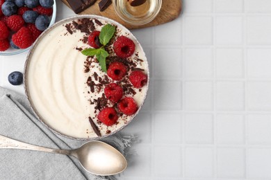 Photo of Tasty cooked semolina porridge with berries served on white tiled table, top view. Space for text