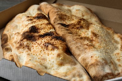 Photo of Delicious calzones in cardboard box on table, closeup