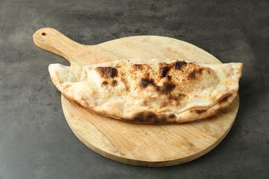 Photo of One delicious calzone on grey textured table