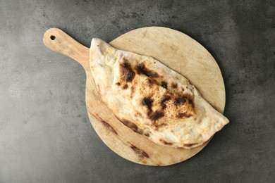 Photo of One delicious calzone on grey textured table, top view