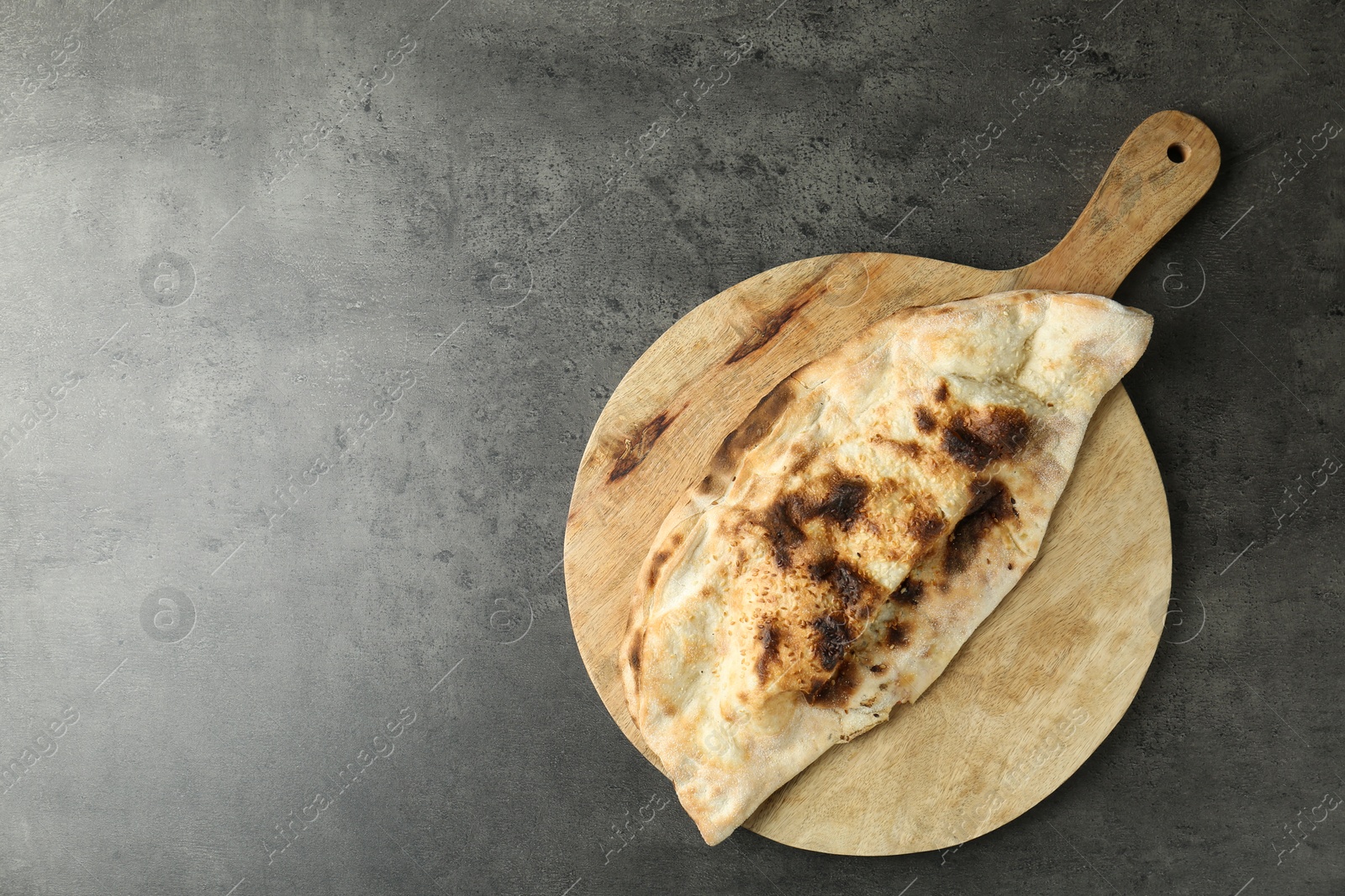 Photo of One delicious calzone on grey textured table, top view. Space for text