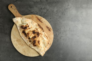 Photo of One delicious calzone on grey textured table, top view. Space for text