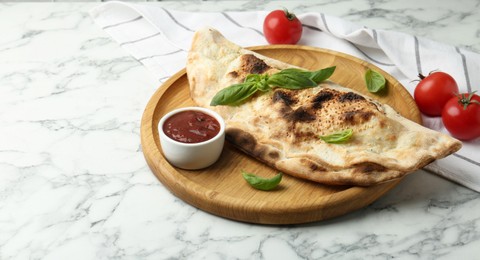 Photo of Delicious calzone served on white marble table, space for text