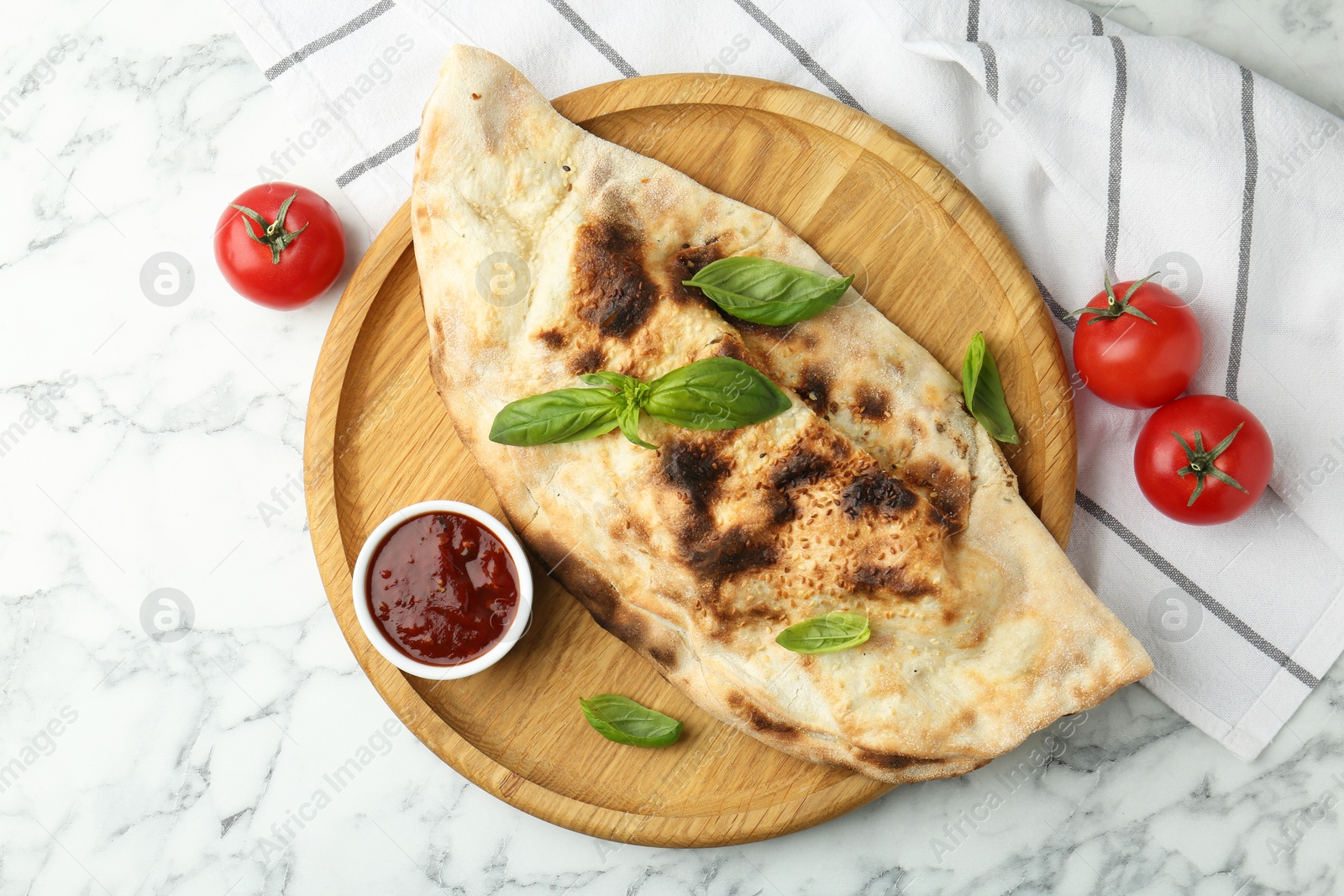 Photo of Delicious calzone served on white marble table, top view