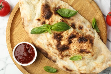 Photo of Delicious calzone served on white marble table, flat lay