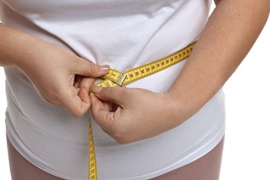 Photo of Weight loss. Plus size woman measuring waist with tape on white background, closeup