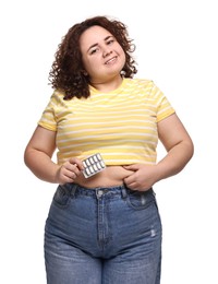 Happy plus size woman with blister of weight loss supplements on white background