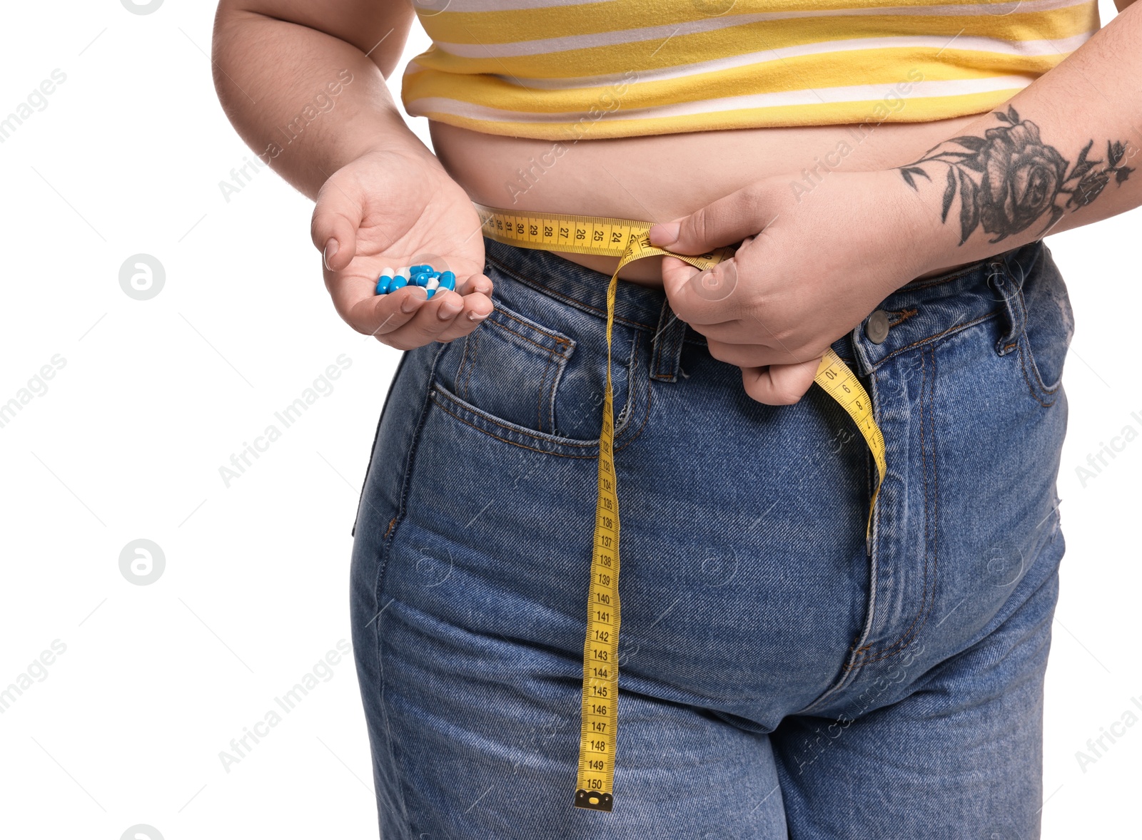 Photo of Plus size woman measuring waist with tape and holding pile of weight loss supplements on white background, closeup