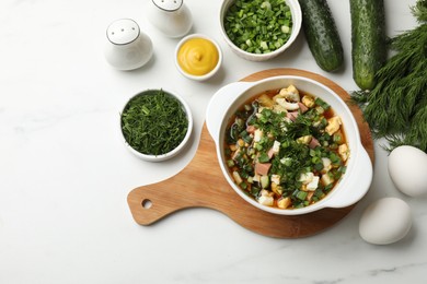 Photo of Delicious okroshka soup and ingredients on white table, flat lay. Space for text