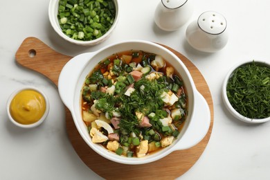 Photo of Delicious okroshka soup and ingredients on white table, flat lay