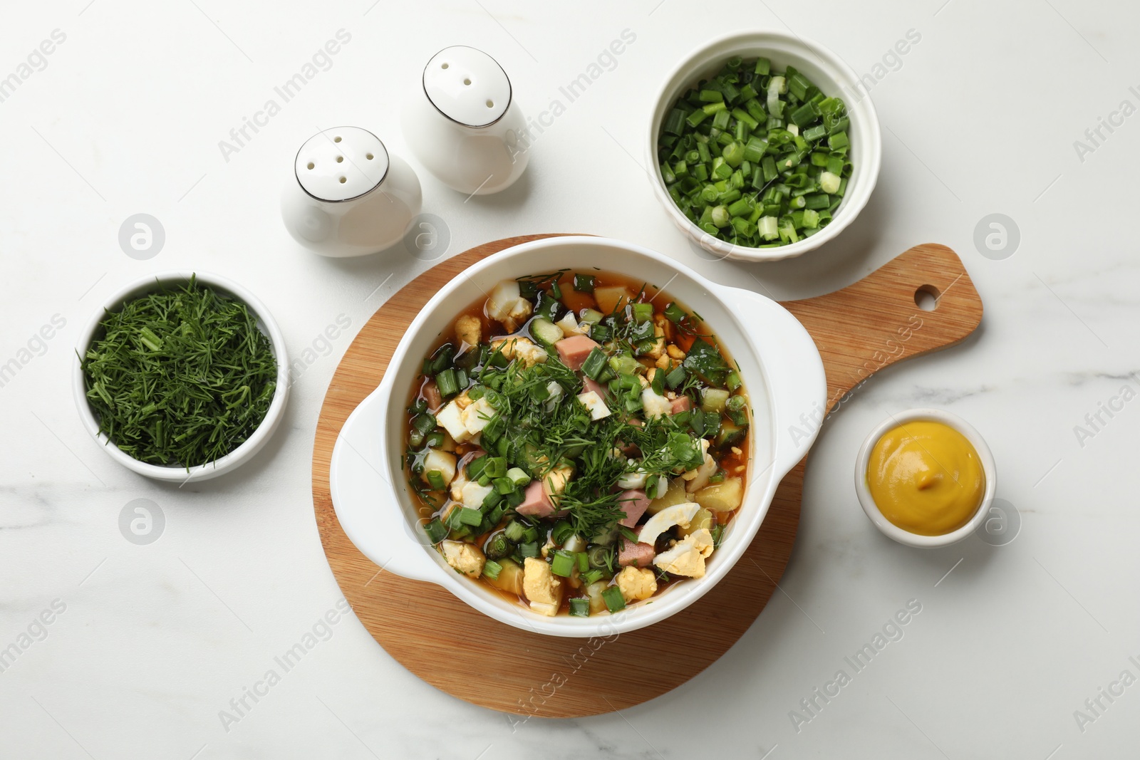 Photo of Delicious okroshka soup and ingredients on white table, flat lay