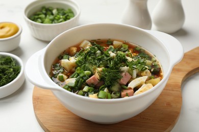 Photo of Delicious okroshka soup and ingredients on white table, closeup