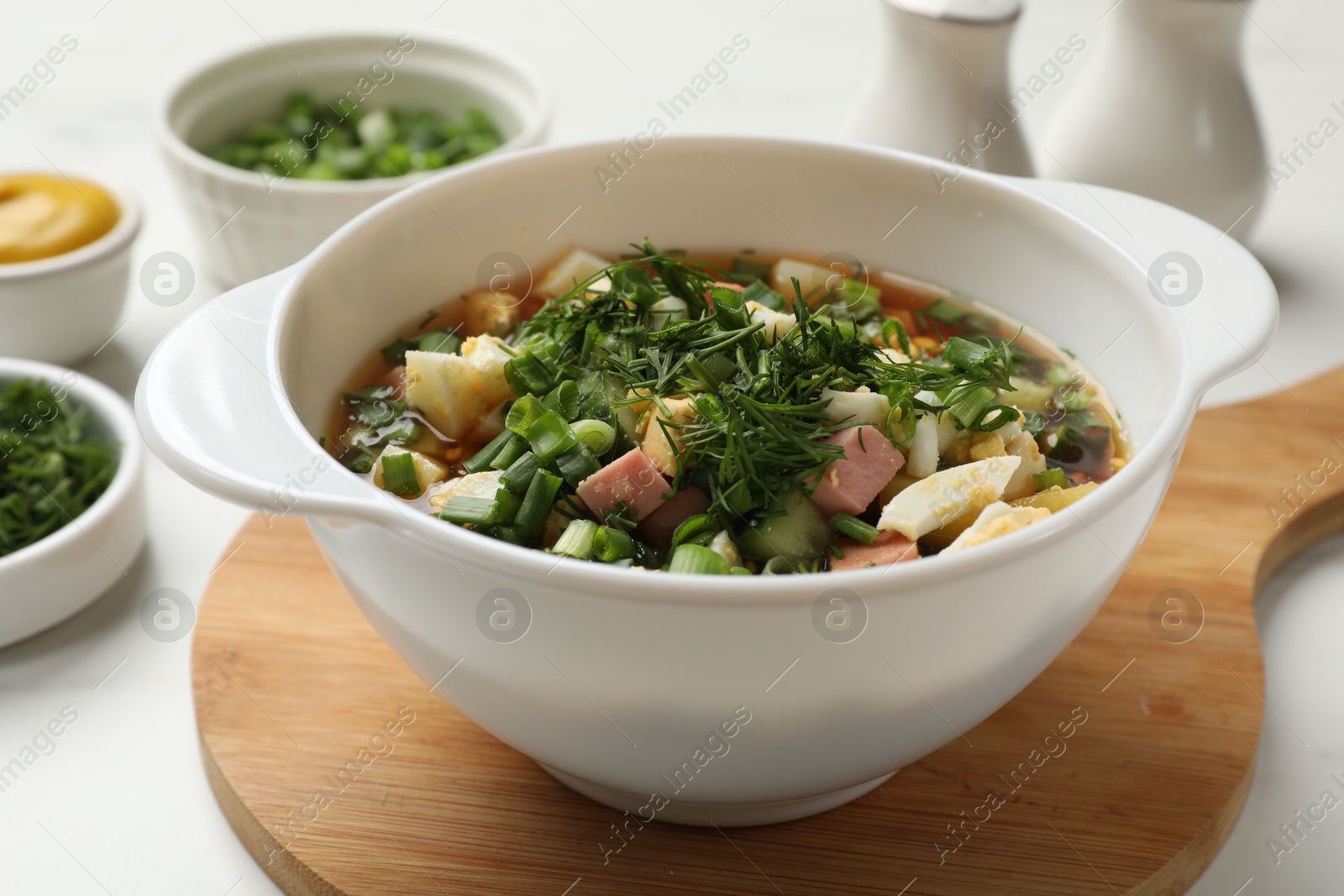 Photo of Delicious okroshka soup and ingredients on white table, closeup